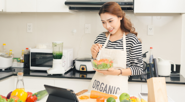 Woman cooking healthy food using recipe on her ipad