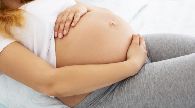 Pregnant woman's belly with her hands laying on top