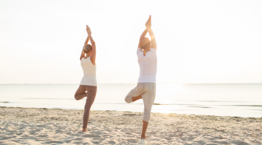 Man and woman doing yoga on the beach